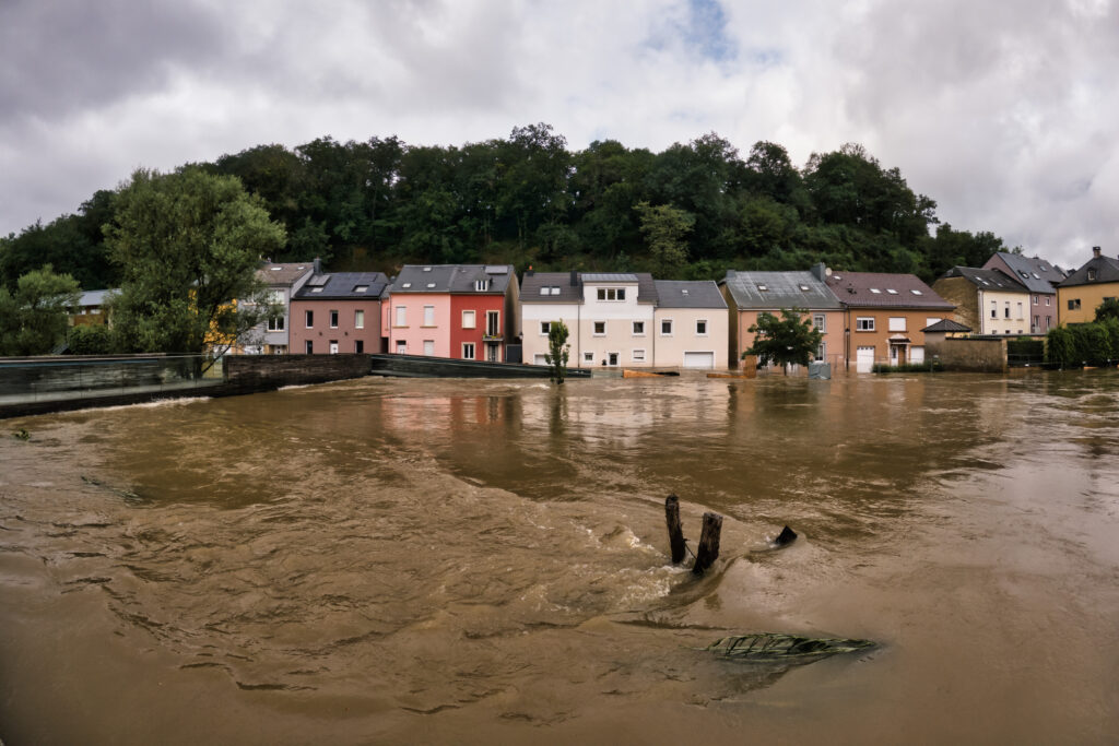 Brown floodwaters with terraced housing in the background
