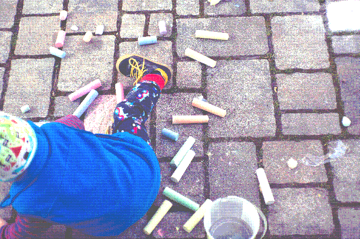 Pixelated image of a child playing with crayons on the street
